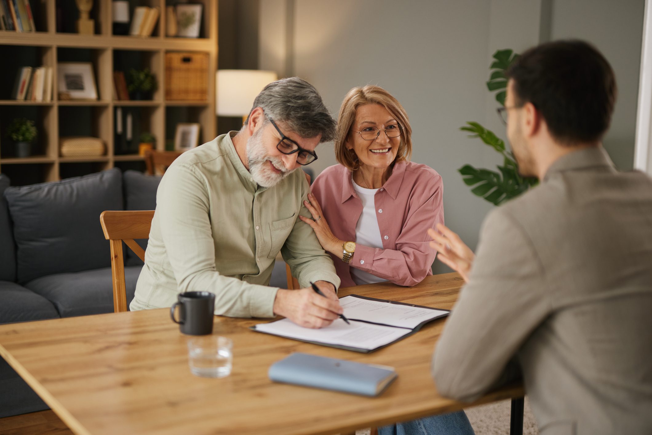 Mature couple discussing life insurance and retirement plans with a financial advisor at home
