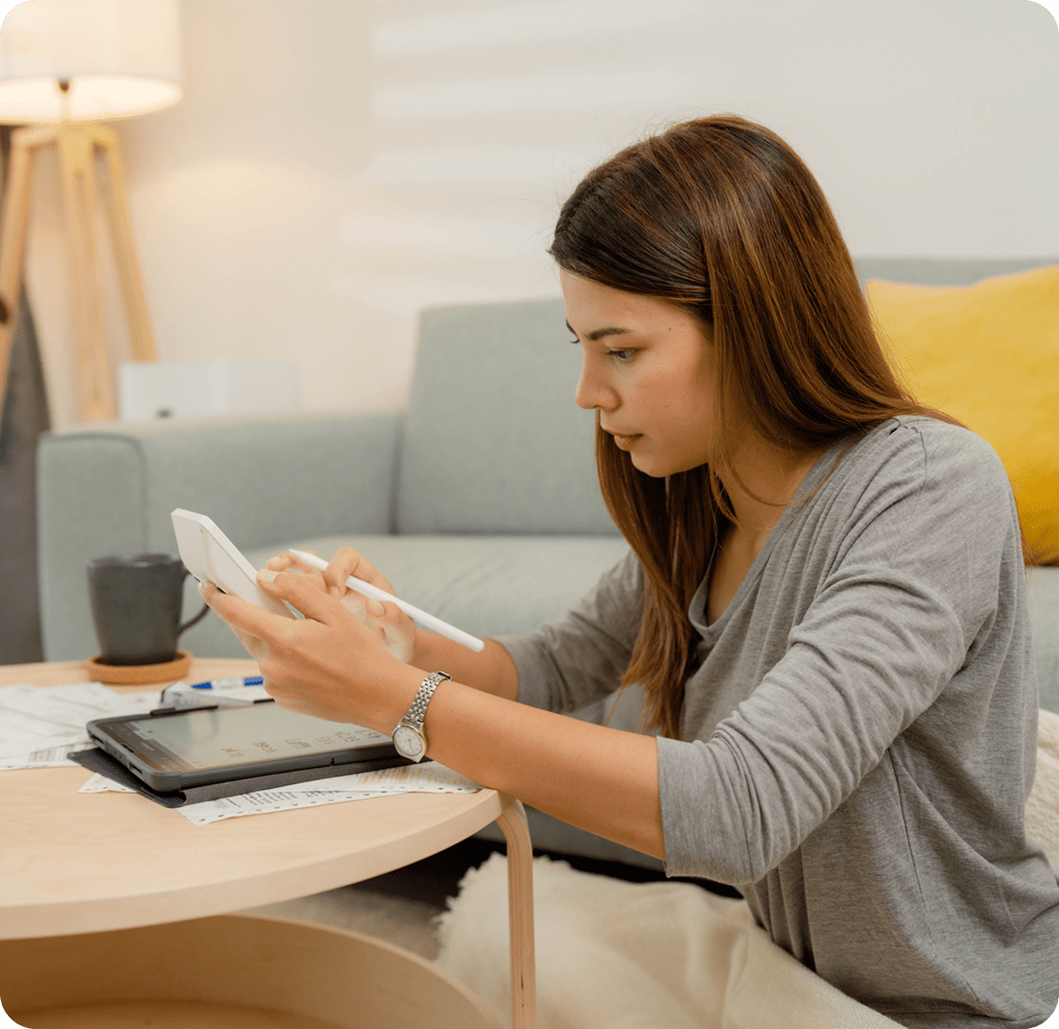 Woman writing with stylus on tablet.
